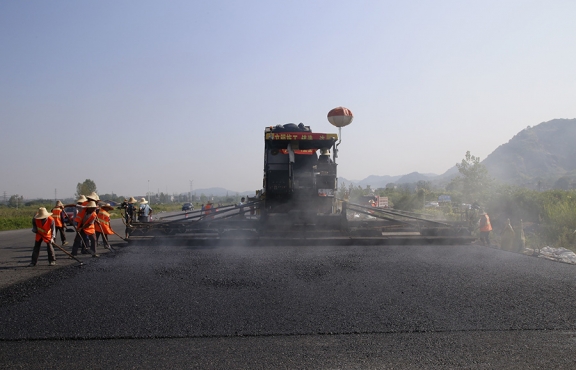 2019年8月，宜春經(jīng)開區(qū)S311路面攤鋪現(xiàn)場，工友們輔助路面兩側(cè)的分料、補窩等作業(yè)